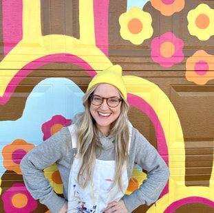 Picture of Tara smiling in front of a colourful flower textile mural 